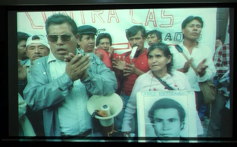Slide 8: A group of protesters. On the right is a man clapping his hands, a megaphone under his arm. Next to him is a woman holding a sign that consists of a younger man's face.