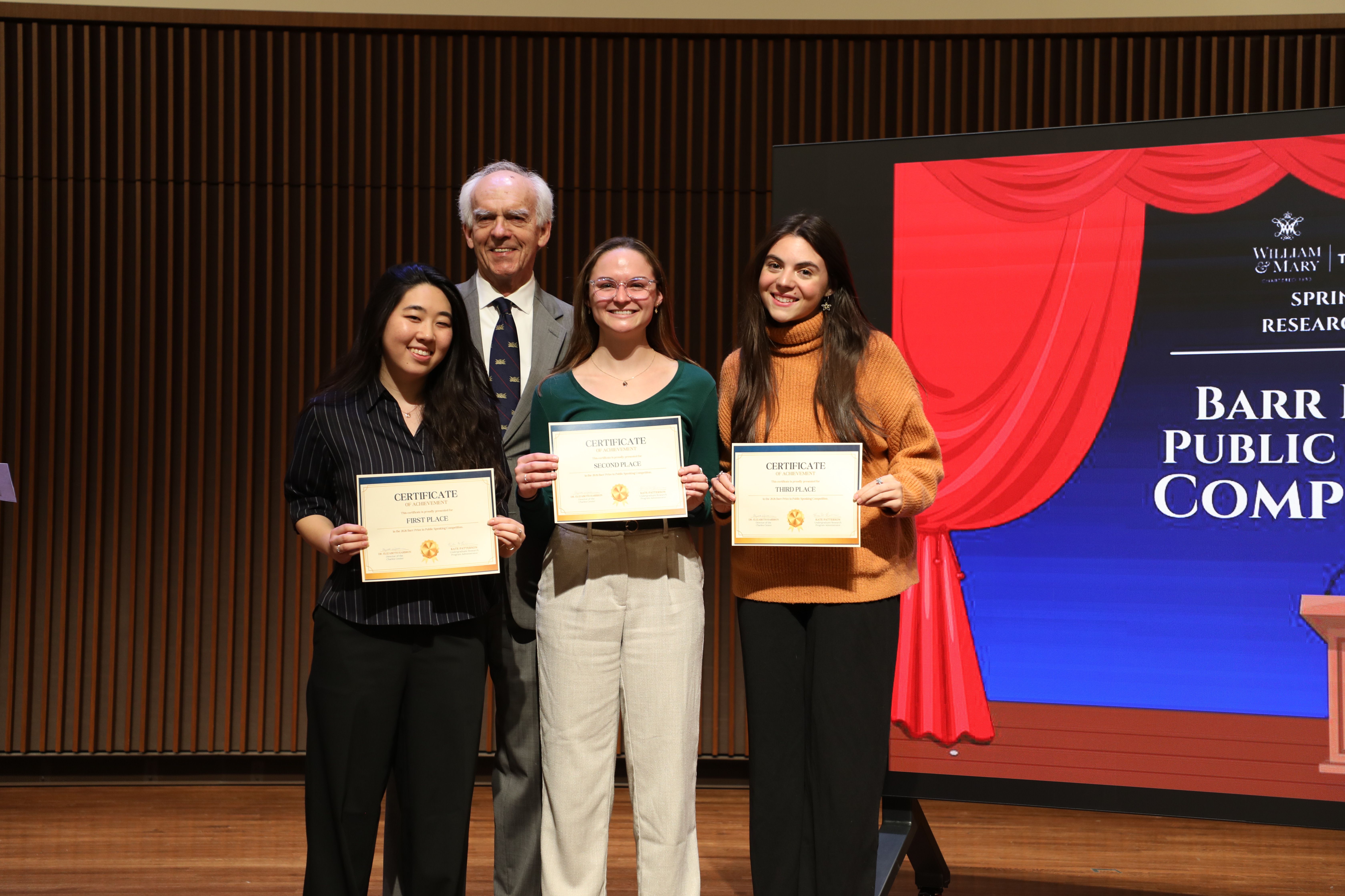 Art and neuroscience double major Caroline Cha '26 (left) garnered first place and a $1,000 prize in this year's Barr Prize in Public Speaking held April 3 in William & Mary's Comey Recital Hall. Also pictured are physics major Julia Rodrigues ‘26 (center), who won the $500 second-place prize, Hannah Ashburn ‘26 (right), an international relations and French & Francophone studies major, who took third place, and Butch Barr '62, the visionary donor behind the competition. (Photo by Adeline Steel)