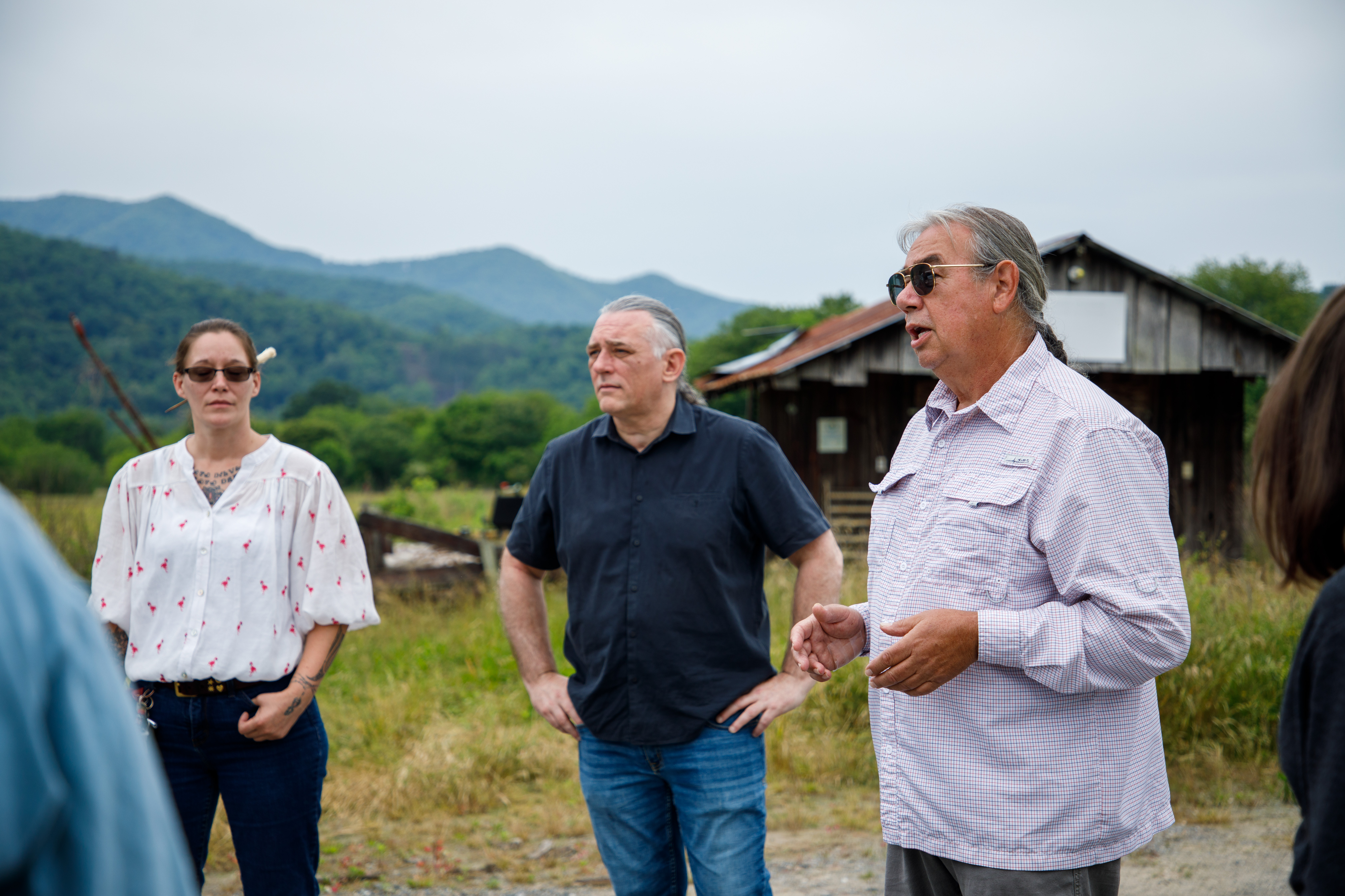 Tribal elder and traditionalist Davy Arch (right) discusses the mother town of Kituwah with the W&M Cherokee Study Away class. Prof. Woodard (center) and tribal member Amanda McCoy (left) look on at the former town's central mound. (Photo by Grace Helmick)
