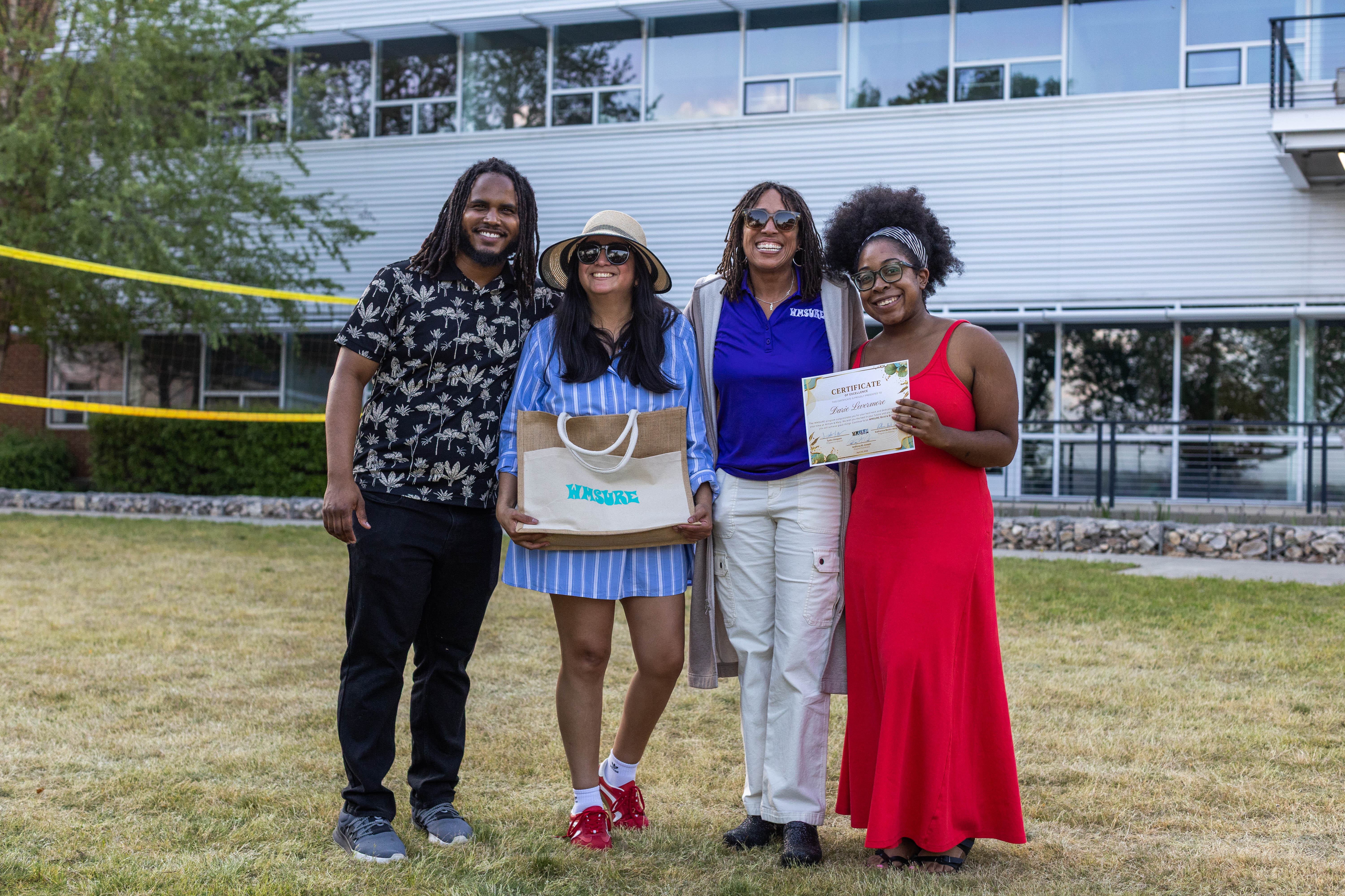 WMSURE Program Coordinator Anthony "AJ" Joseph, Co-Director Katherine Barko-Alva, and Co-Director Iyabo Osiapem (left to right) present Darie Levermore ’25 with a certificate of excellence at the program's end of year celebration April 30. (Photo by Tess Willett)