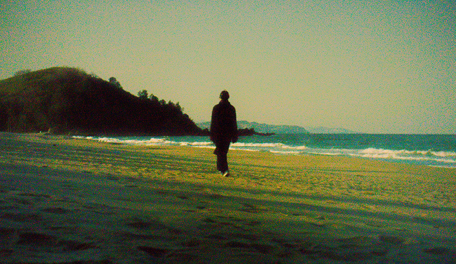 A photograph of a movie scene depicting a woman on a beach walking alone