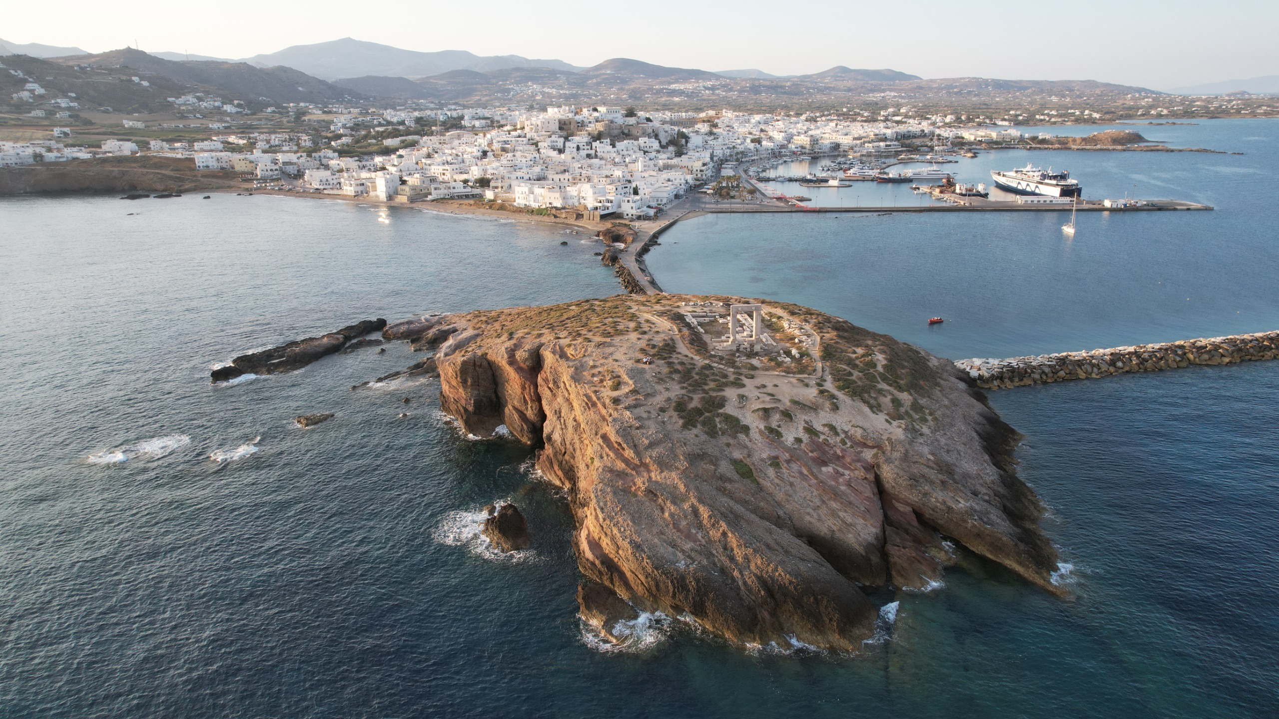 Drone photo of the Palatia islet with the “Portara” unfinished temple remains and the town of Chora, Naxos, in the background (photo by Evan Levine).
