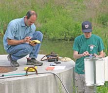Greg Hancock of W&M's Geology Department (left), assisted by student Marshall Popkin, collects data at a stormwater retention pond in James City County.