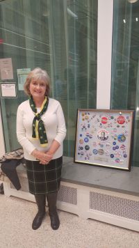 Donna Robusto Krache '78 poses in front of her late husband, David Karuche's political button collection