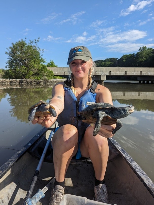 research student holding two turtles in a canoe