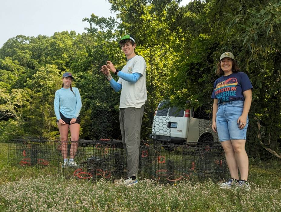 three research students standing behind crab pots