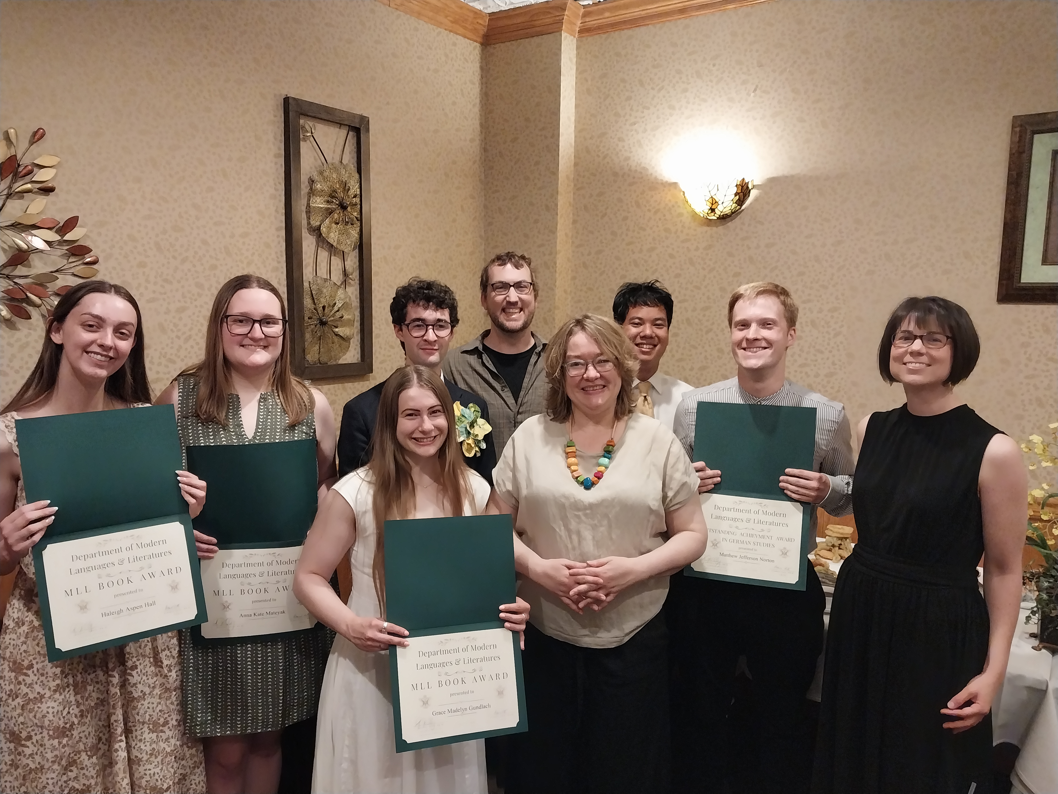 Students standing in semi-circle with award documents