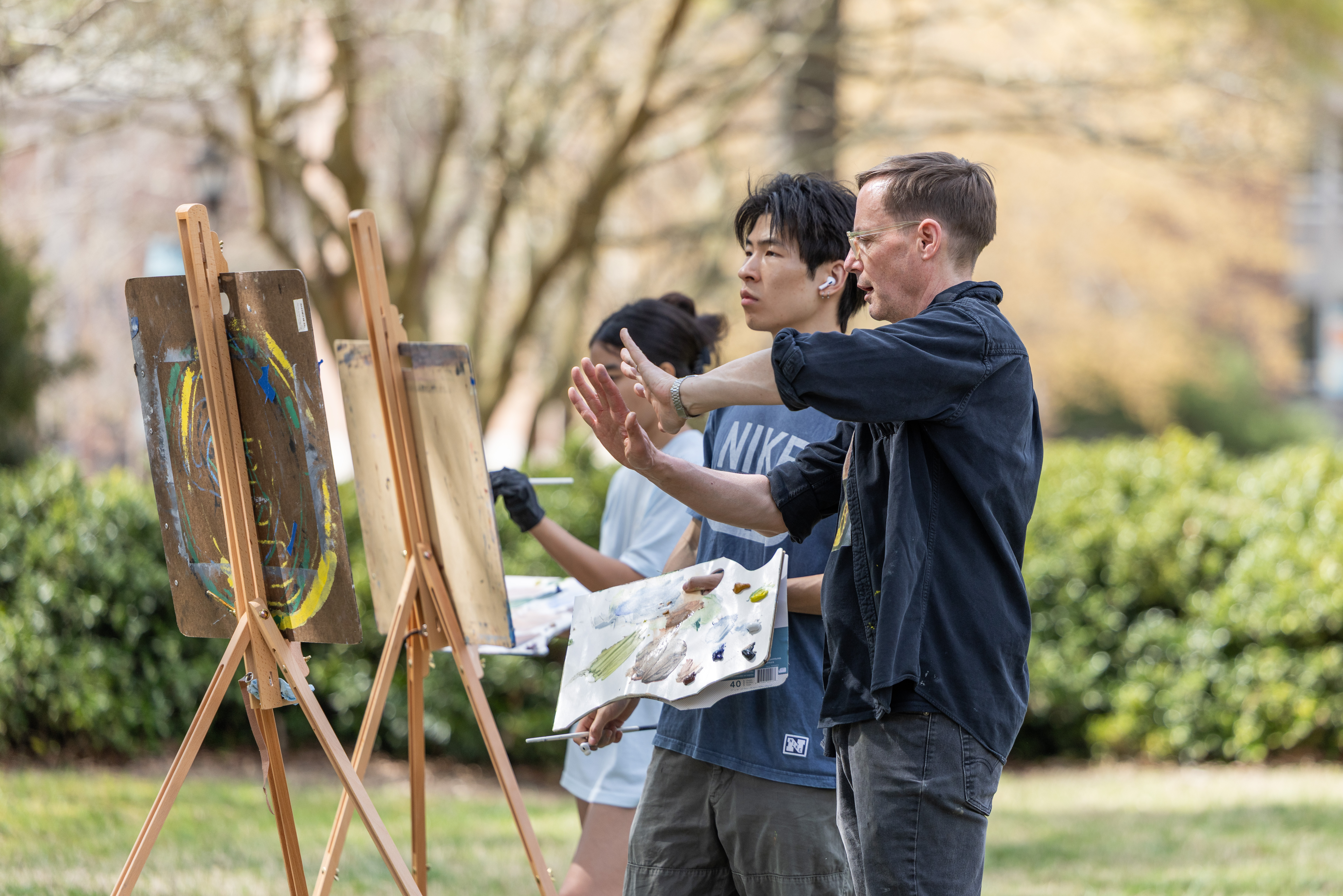 John Lee, associate professor of art, examines a student's painting and provides guidance. Photo by Katie Warner.