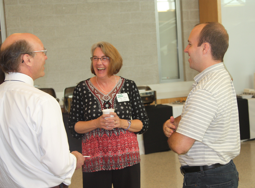Professor Burk and Professor Hunt share a laugh with an alum during the Homecoming Open House