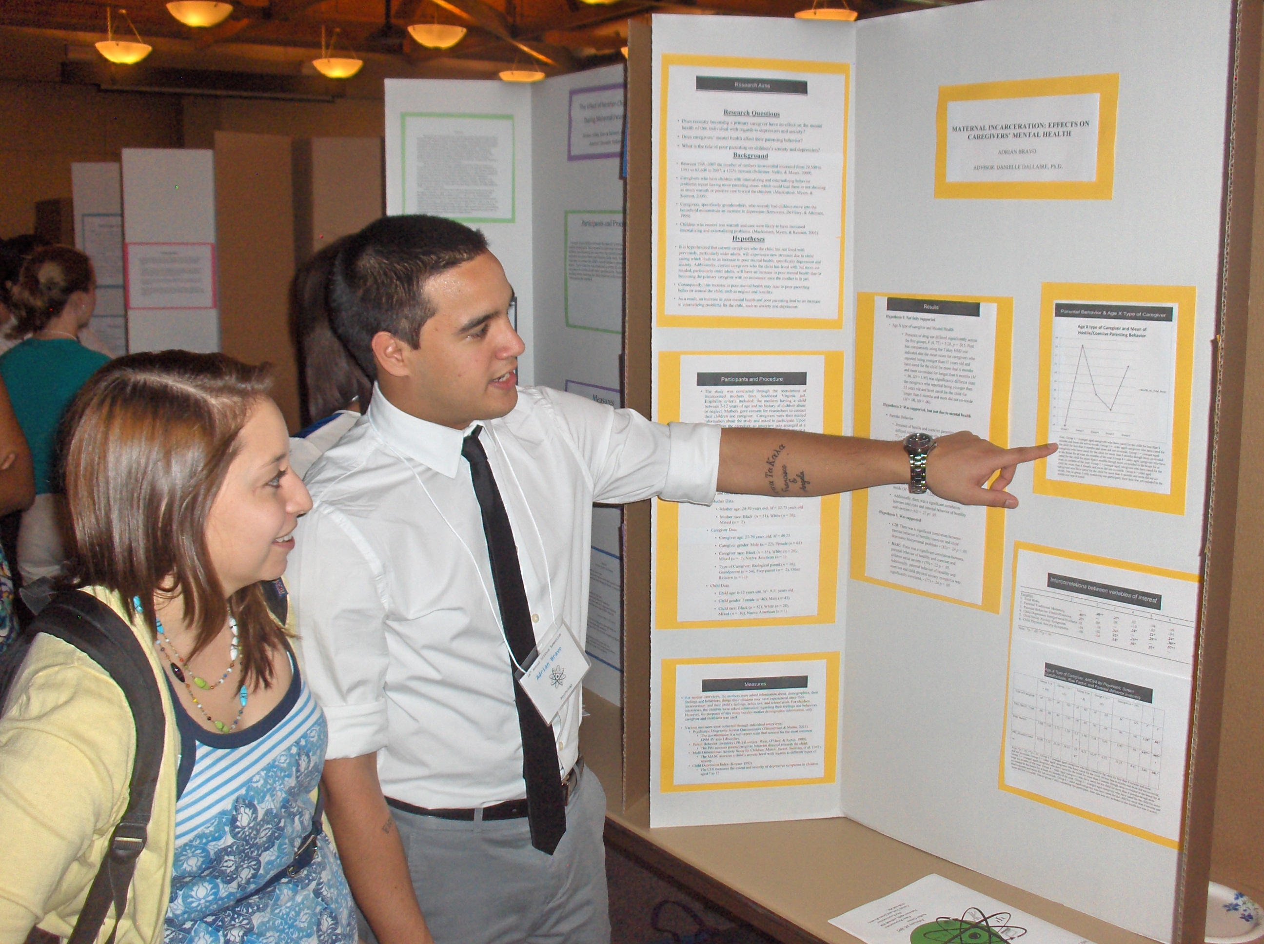 Adrian Bravo shows a friend his poster on Maternal Incarceration Effects on Caregivers' Mental Health