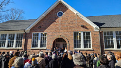 A crowd of community members, alumni, board members, and journalists gather outside the Impact Center, formerly Cape Charles Elementary, for a ribbon cutting ceremony. 