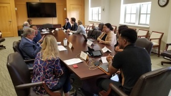 Small group policy discussions with board members and MPP students focusing on health policy (foreground) and environmental policy (background).