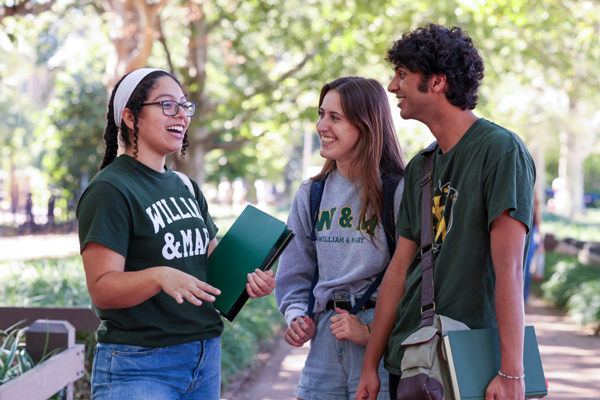 Three students smiling and talking outside on campus