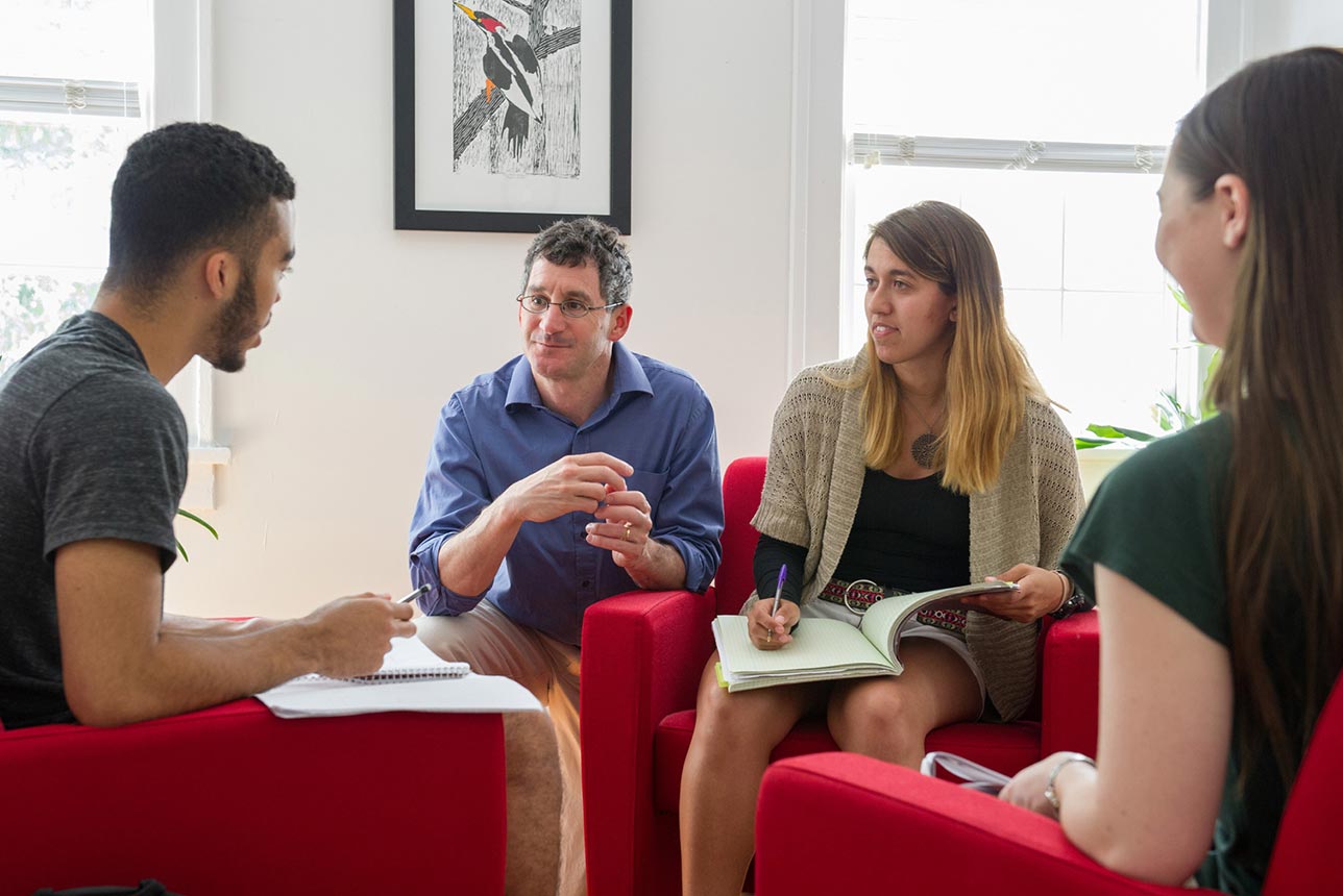 A professor and three students seated in a circle