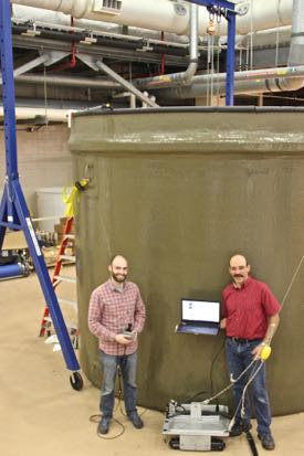 Dale McElhone and Paul Panetta with their Acoustic Slick Thickness ROV, in front of the 8,460-gallon tank they used for testing the vehicle inside VIMS' Seawater Research Laboratory.