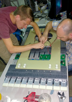 Devin Moore ’19 (left) and machine shop director Will Henninger work on the prototype high voltage test at Fermilab.