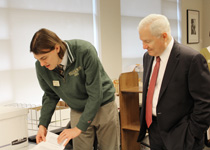 Graduate student assistant Jim Rick M.A. ’17, Ph.D. ’22 (left) shows Chancellor Gates photos in the collection taken during his term as university president at Texas A&M. (Photo by Tami Back, University Libraries)