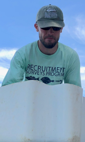 Brian Gallagher, chief scientist for the Juvenile Striped Bass Seine Survey at VIMS, examines the haul from a tow in the James River. (Photo by D. Malmquist/VIMS)