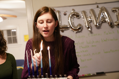 Lucy Greenman '22 leads participants in a song while she lights a menorah. (WYDaily/Courtesy Stephen Salpukas)