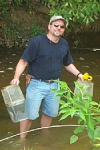 Mark LaGuardia collects samples from a freshwater stream for analysis of flame retardants.