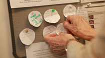 Sharon Zuber tacks up positive messages submitted by students about their experiences at the Writing Resources Center. (Photo by Stephen Salpukas)