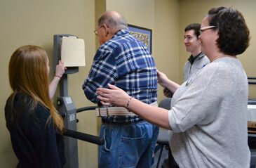 John Marsh ’55 steps on the Biodex Balance System watched by Adin Pace ’97. CBAS students Jessica Pitts ’19 and Kendall Bayless ’19 prepare to record his balance performance. (Photo by Joseph McClain)