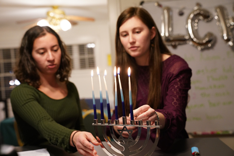 Two students light a menorah in the Shenkman Jewish Center. (Photo by Stephen Salpukas)