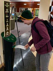 A students pulls a story from the dispenser. (W&M Libraries photo)