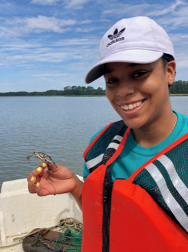 REU student Thalia Wallace enjoys her first encounter with a blue crab. (VIMS photo)