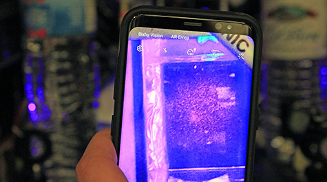 A cellphone camera held in front of an atomic imaging station shows a scattering of atoms inside William & Mary’s Ultracold AMO Physics Laboratory. 