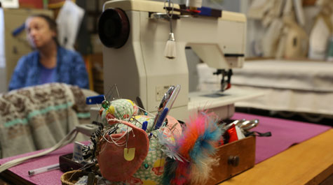 Sewing machine with pink pincushion full of pins, feathers