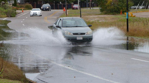 A car drives through a flooded roadway