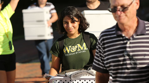 A new student carries belongings to her dorm