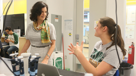 Katherine Rowe talks with a student in a lab with equipment around them