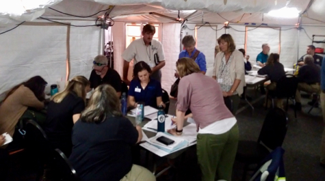 People work together around tables inside of a tent