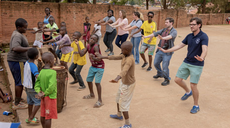 College students dance with children in an outdoor location
