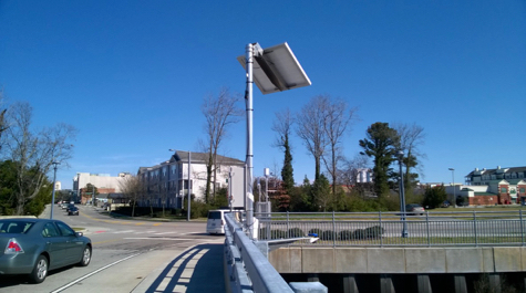 A sensor sits on top of a pole on a bridge