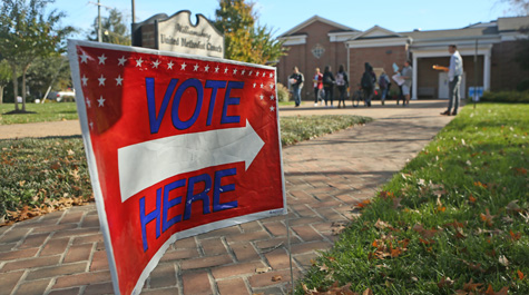 A sign saying Vote Here points down a brick pathway
