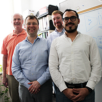 Team of computer scientists stands in front of whiteboard