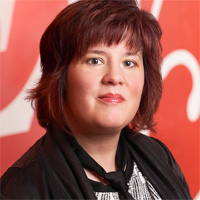 Jen Chaney looks at the camera while standing in front of a red background