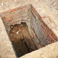 A hole in the ground shows a vaulted brick drain