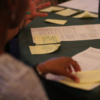 A person holding one of several papers on a tabletop