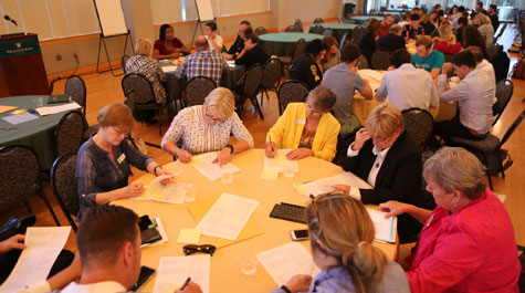 Groups of people at tables writing down their ideas on paper