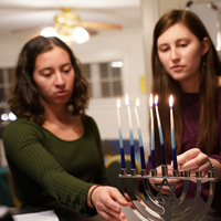 Two students light a menorah