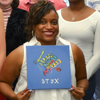 Shantá Hinton sits in the center of her summer lab students, holding an artist’s rendering of STYX.