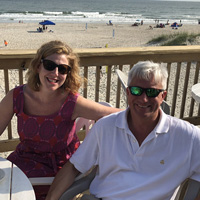 Ali Gaidies Joy and Austin Joy sit on a deck in front of a beach