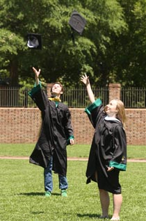 Two graduates throw their caps in the air. (Photo by Stephen Salpukas)