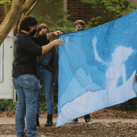 Lecturer of Art Eliot Dudik (left) and students look at one of the cyanotype project components. (Photo by Stephen Salpukas)