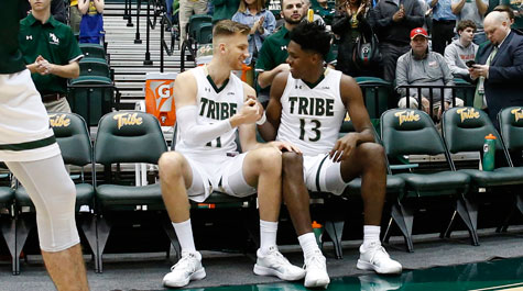 Andy Van Vliet and Nathan Knight shake hands while sittting on the bench