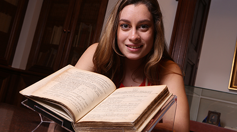 Caitlin Dolt stands beside the Swem Special Collections' copy of Isaac Newton’s “Principia.” 